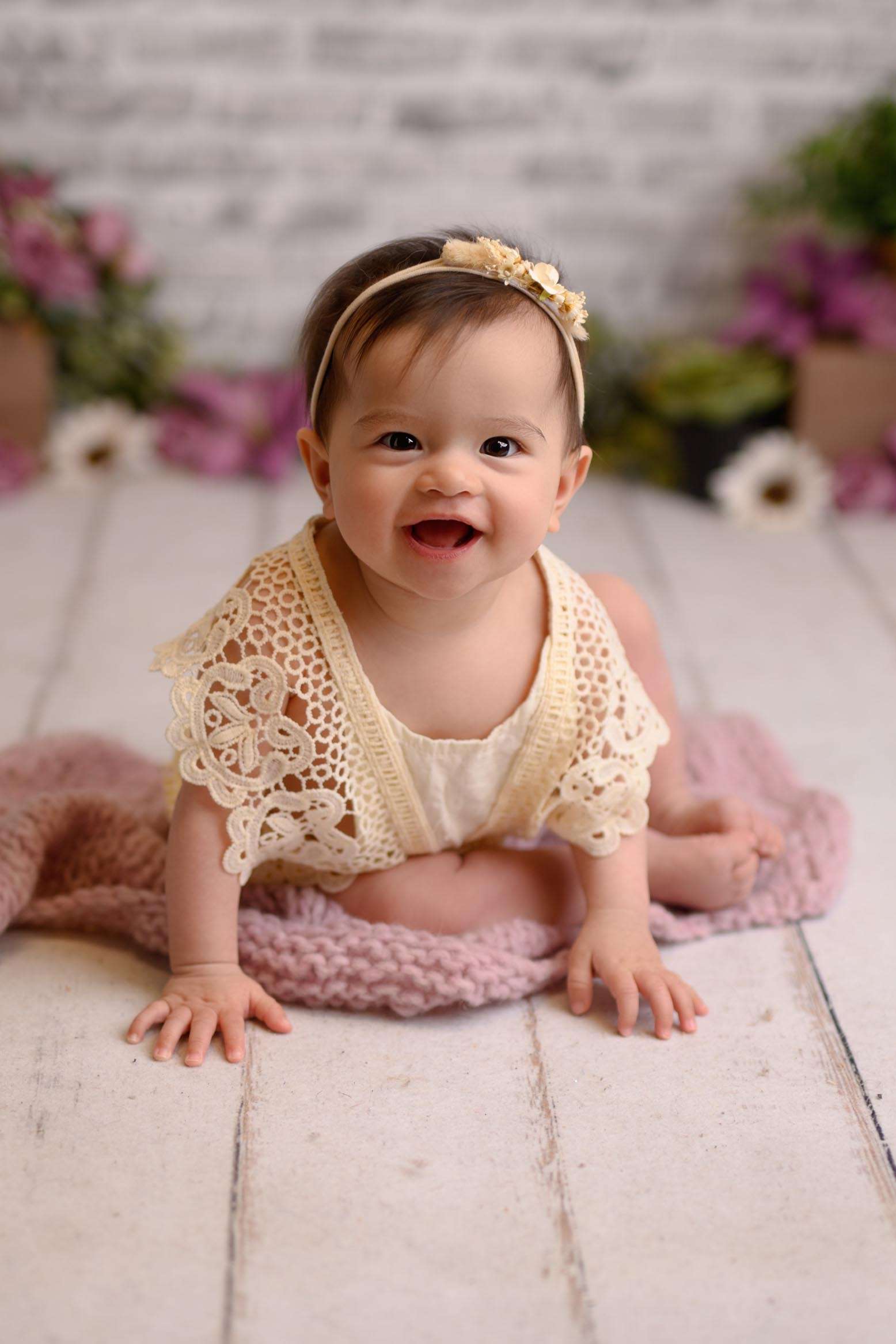 6 months old baby girl on the white wooden floor at the photo studio in san diego