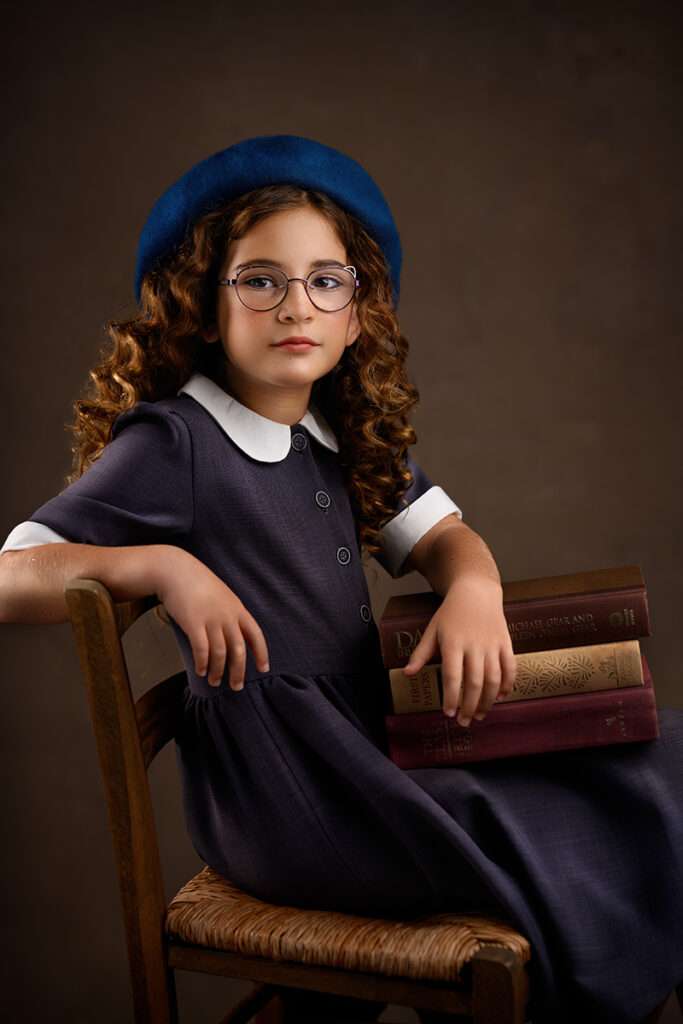 studio portrait of a girl wearing blue beret and grey dress and holding books by best san diego family photographer