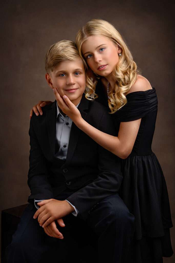 portrait of brother wearing black suit and sister wearing black dress by san diego family photographer